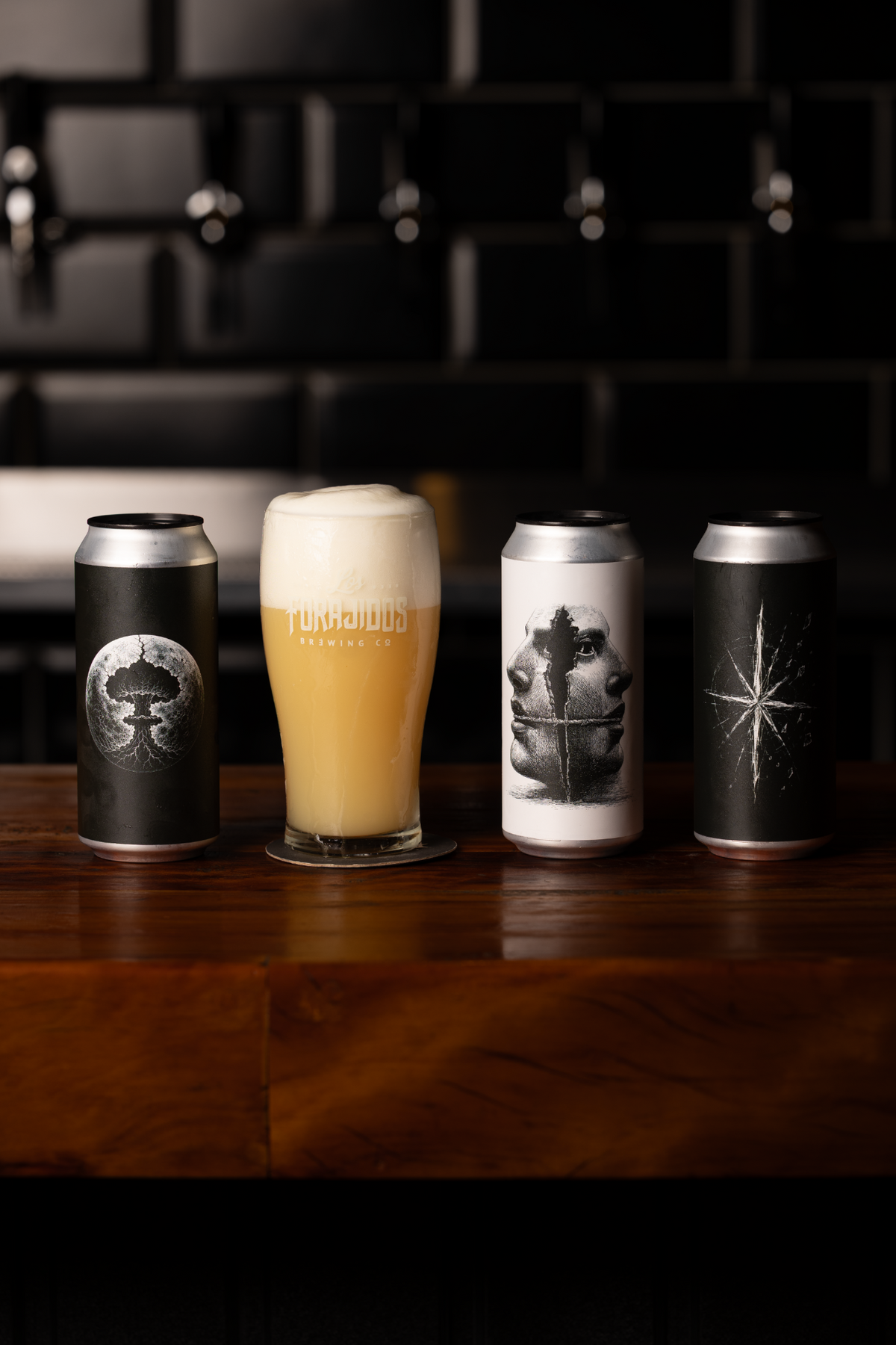 Três cervejas Los Forajidos e copo de cerveja sobre o balcão