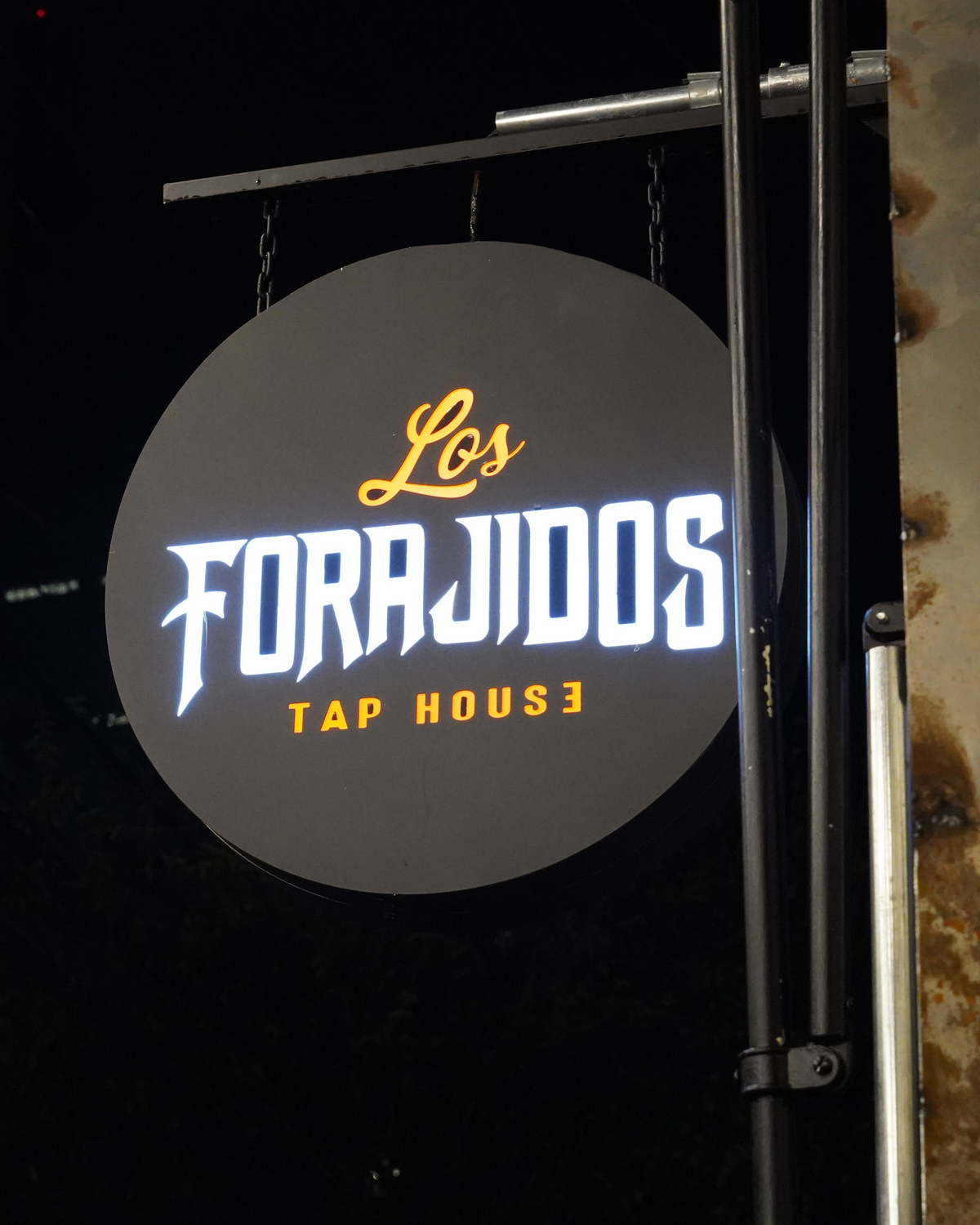 Placa iluminada Los Forajidos Tap House em enquadramento vertical